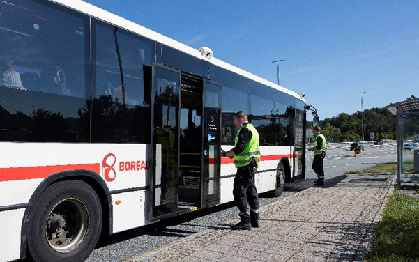 Kontrollører går inni buss. Foto.